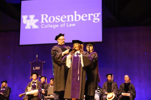 Law Graduate Gives Thumbs Up While Being Hooded by Faculty at commencement ceremony
