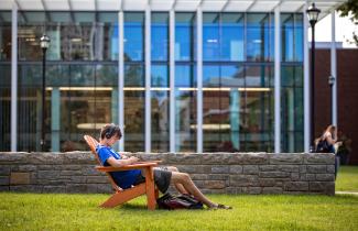 Student relaxing in front of Law Building