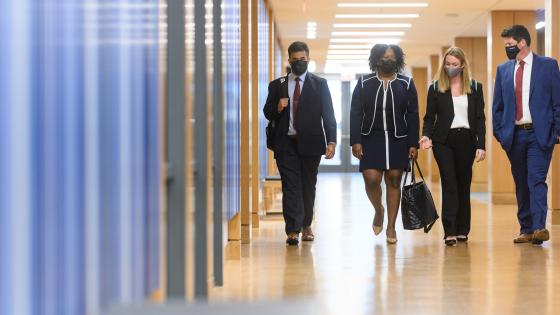 four students in business attire walking down hallway 