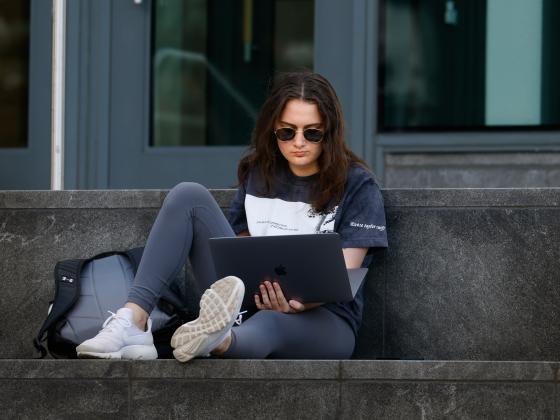 student using laptop outside Law building