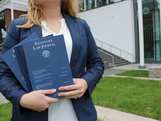 woman in blazer holding law journal