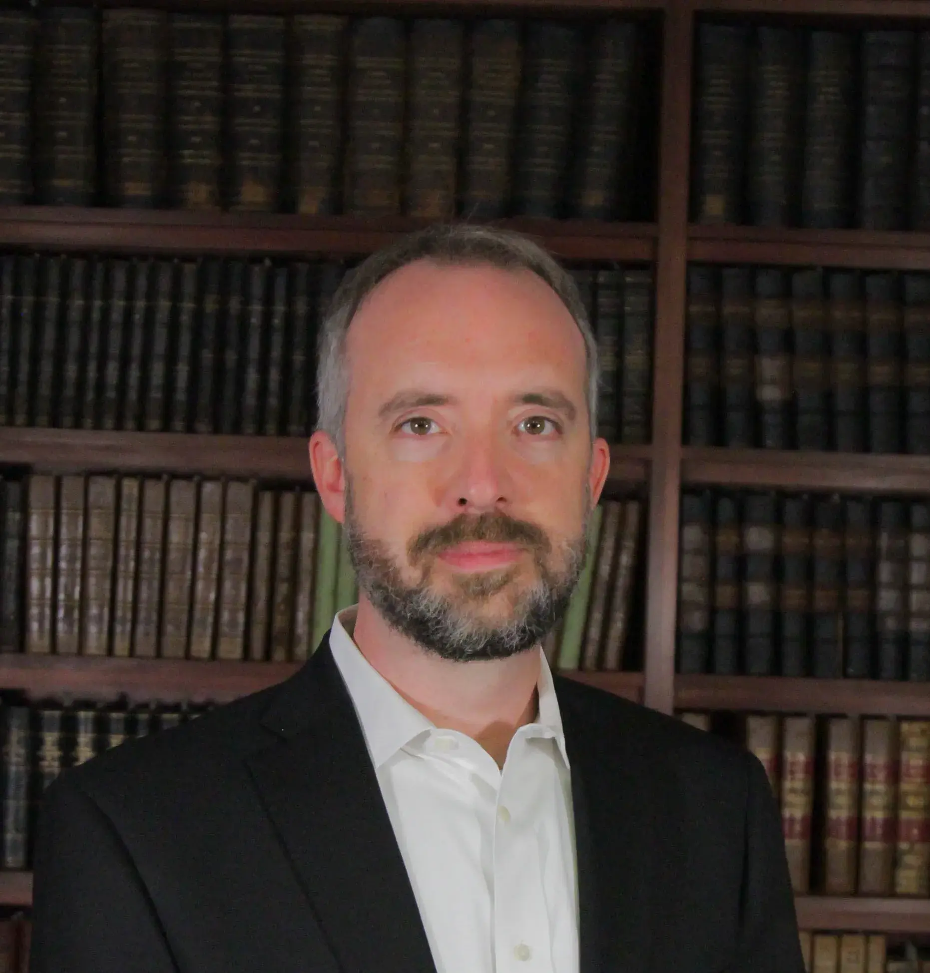 Photo of John Blevins in front of bookcase.